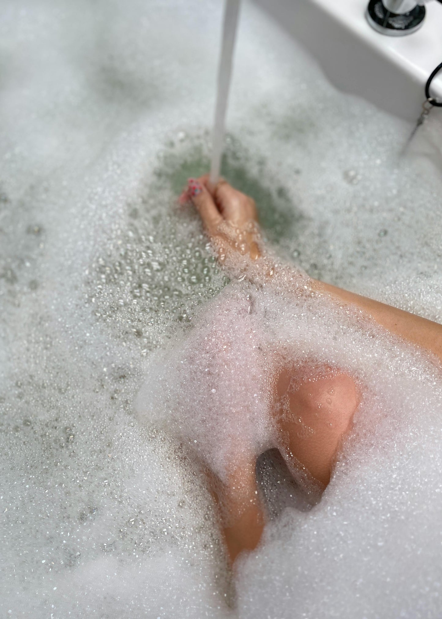 Person's foot in a bathtub filled with bubbles