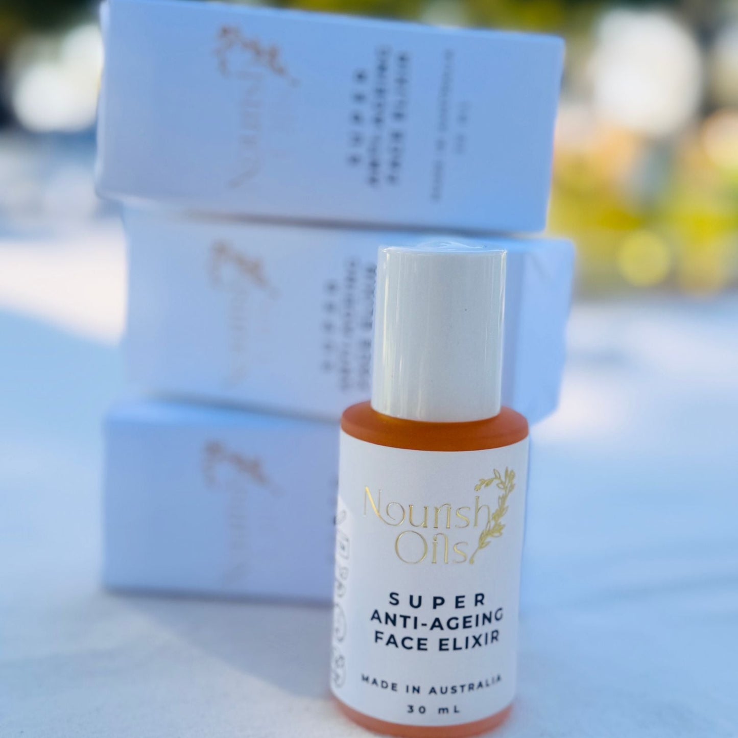 Bottle of 'Super Anti-Ageing Face Elixir' with packaging on a blurred natural background