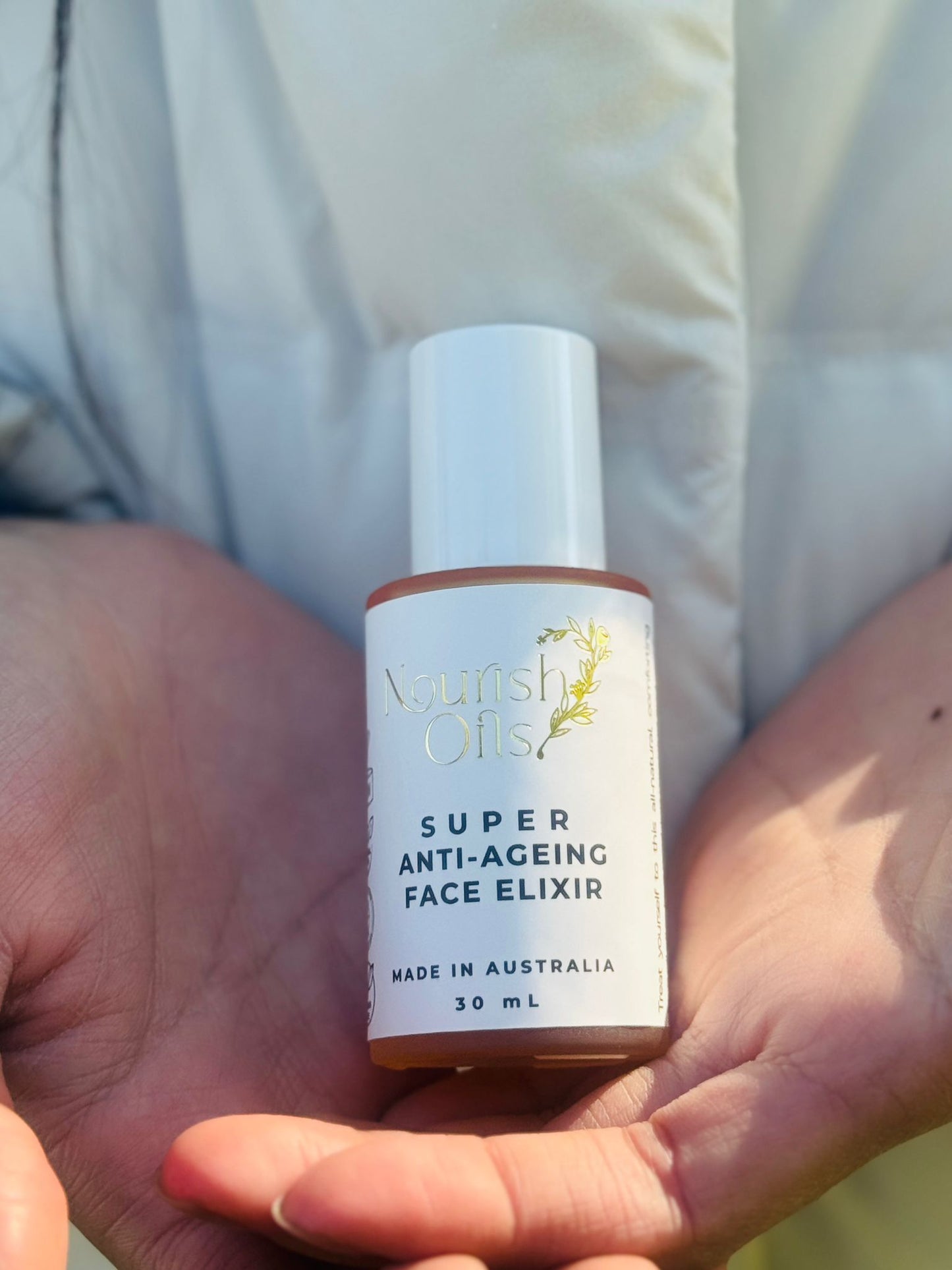 Bottle of 'Super Anti-Ageing Face Elixir' held in hands with a blurred background