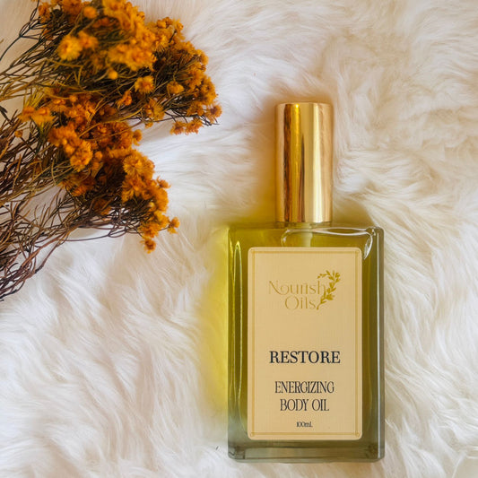 Restore Body and Massage Oil by Nourish Oils in a rectangular glass bottle with a gold cap, featuring an energizing blend of grapefruit and bergamot for immune support and vitality.