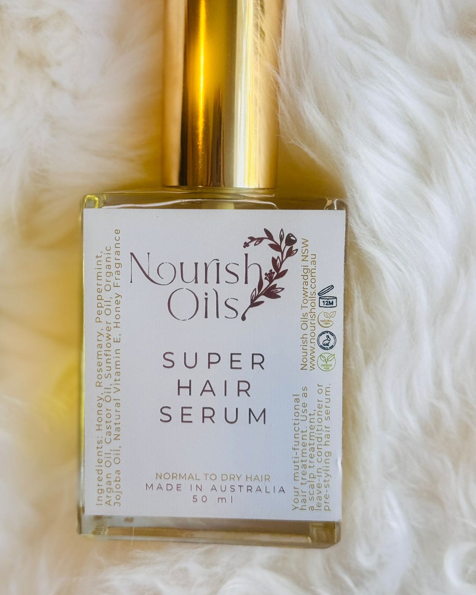 Bottle of Nourish Oils Super Hair Serum on a white fur background