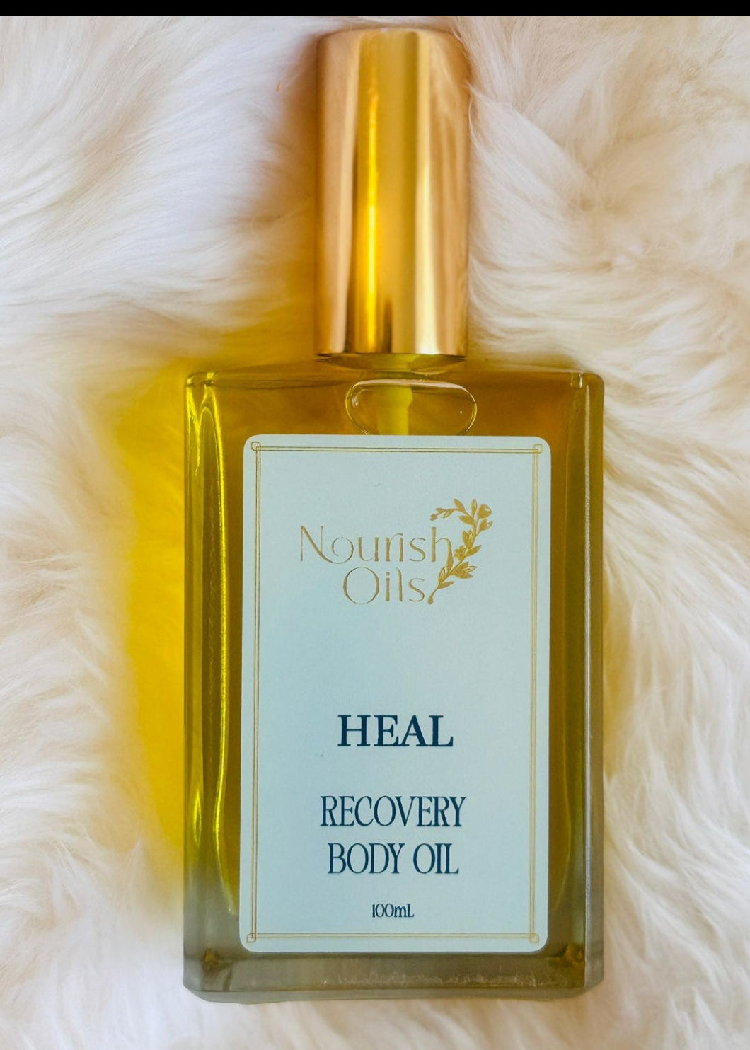Heal Body and Massage Oil by Nourish Oils in a rectangular glass bottle with gold cap, enriched with arnica, peppermint, and turmeric oils to soothe sore muscles, reduce inflammation, and support body recovery. A natural wellness blend for pain relief and deep tissue nourishment.
