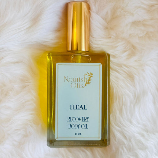 Heal Body and Massage Oil by Nourish Oils in a rectangular glass bottle with gold cap, enriched with arnica, peppermint, and turmeric oils to soothe sore muscles, reduce inflammation, and support body recovery. A natural wellness blend for pain relief and deep tissue nourishment.
