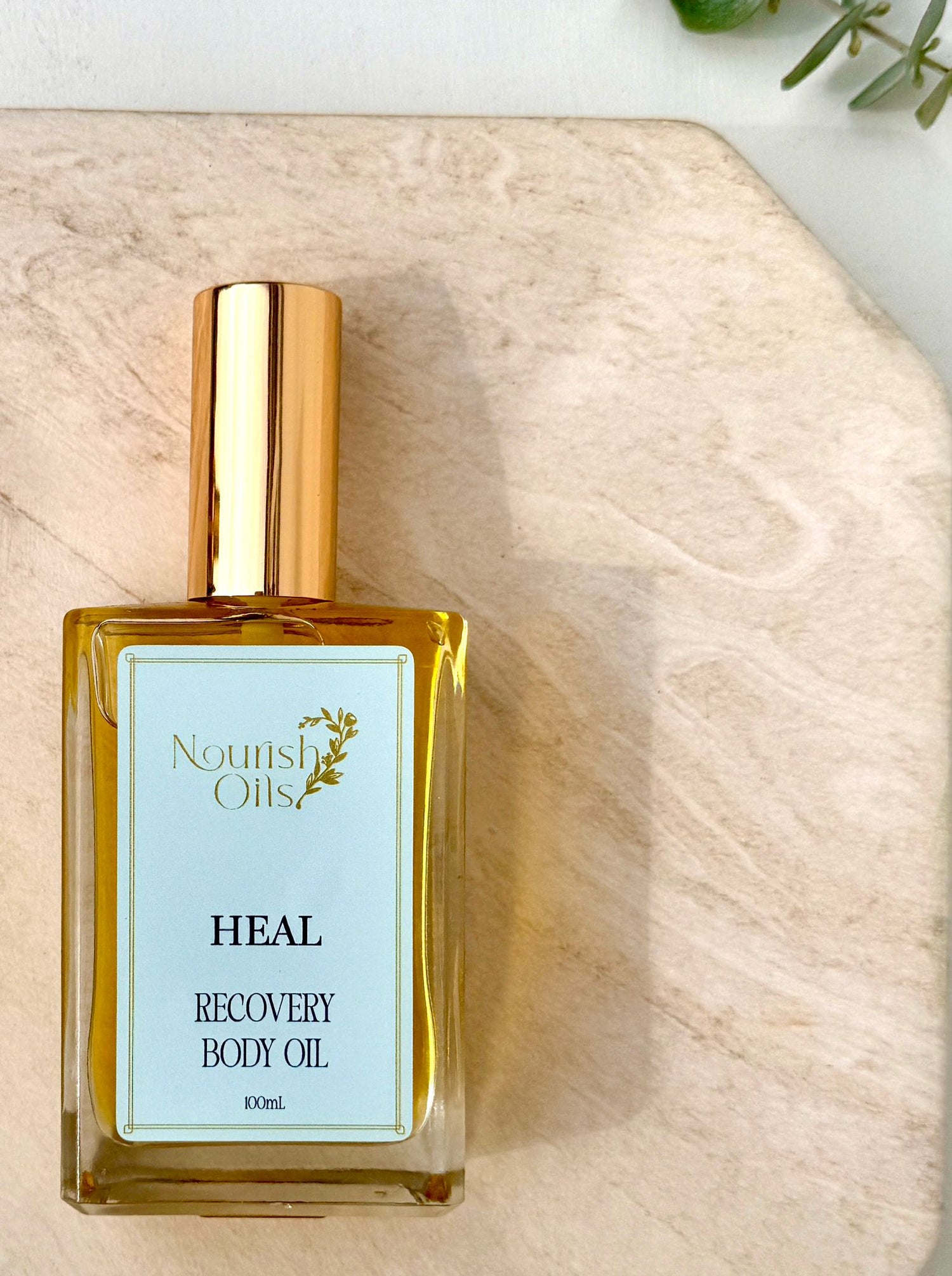 Bottle of Nourish Oils Heal Recovery Body Oil on a wooden surface