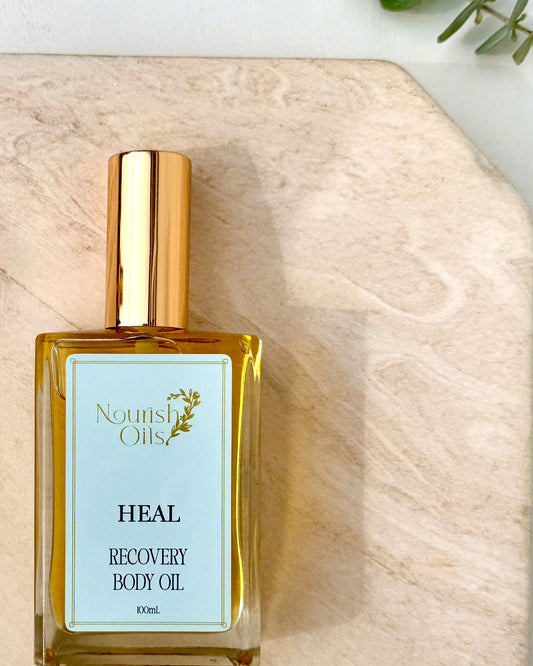 Bottle of Nourish Oils Heal Recovery Body Oil on a wooden surface