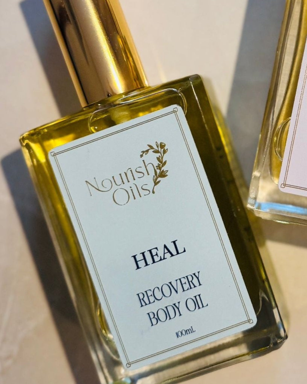Two bottles of best selling Nourish Oils body oil on a light background