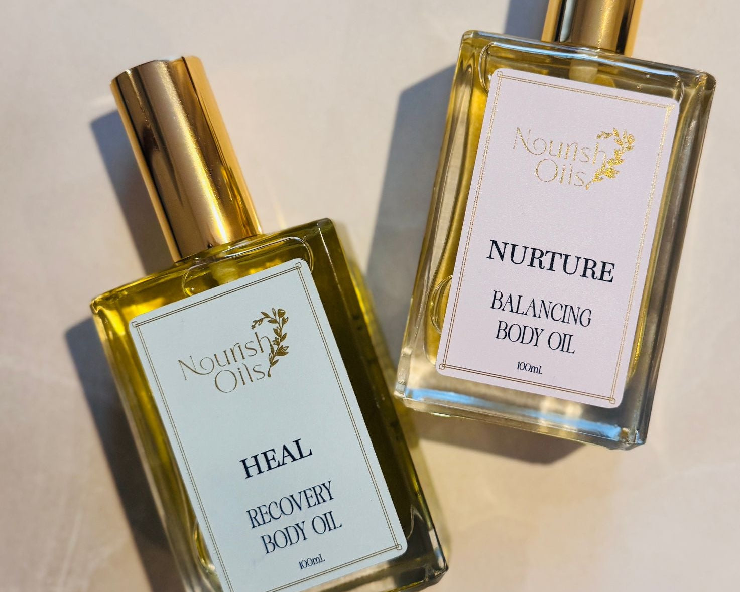 Two bottles of Nourish Oils body oil on a light background