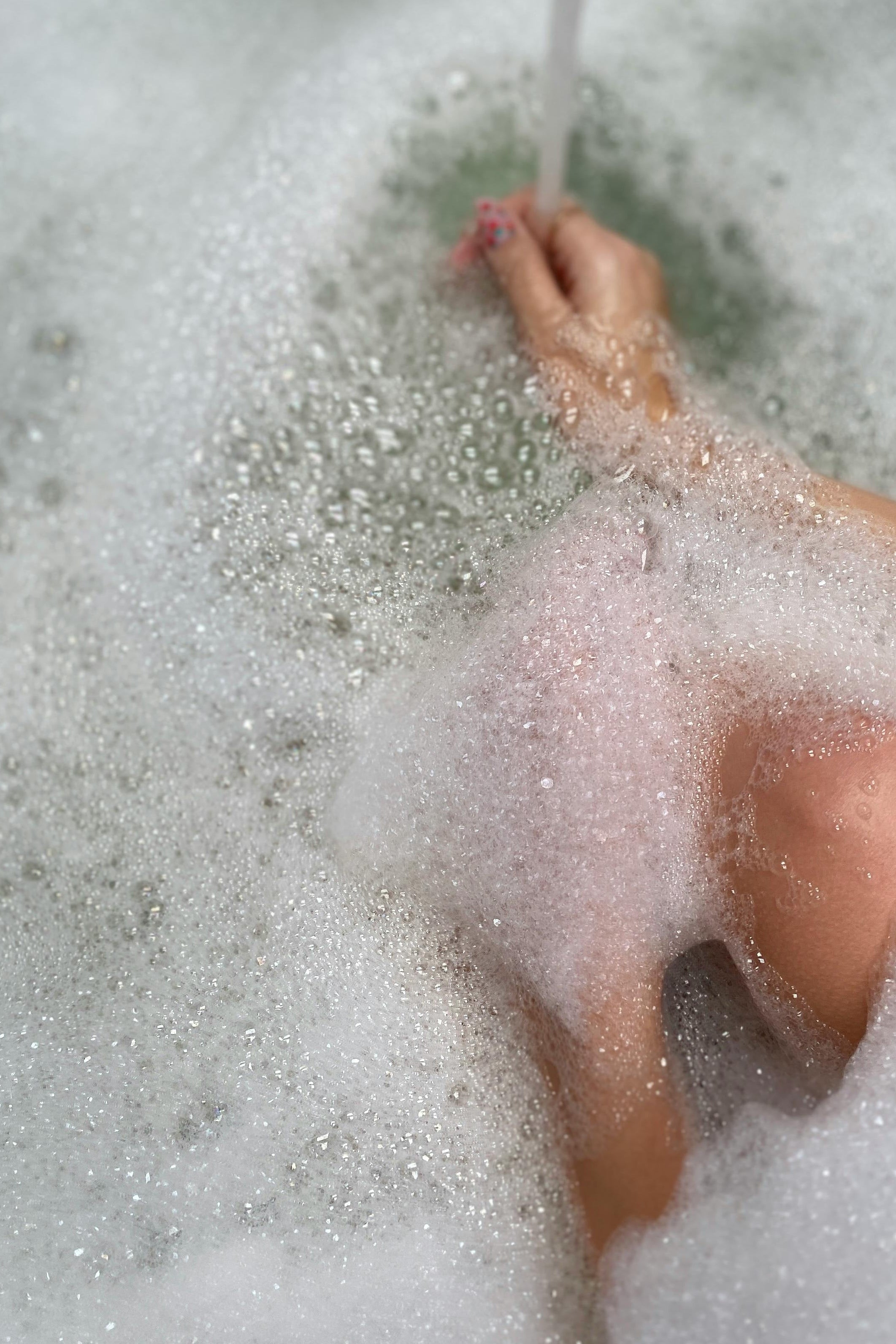Person's foot in a bathtub filled with bubbles