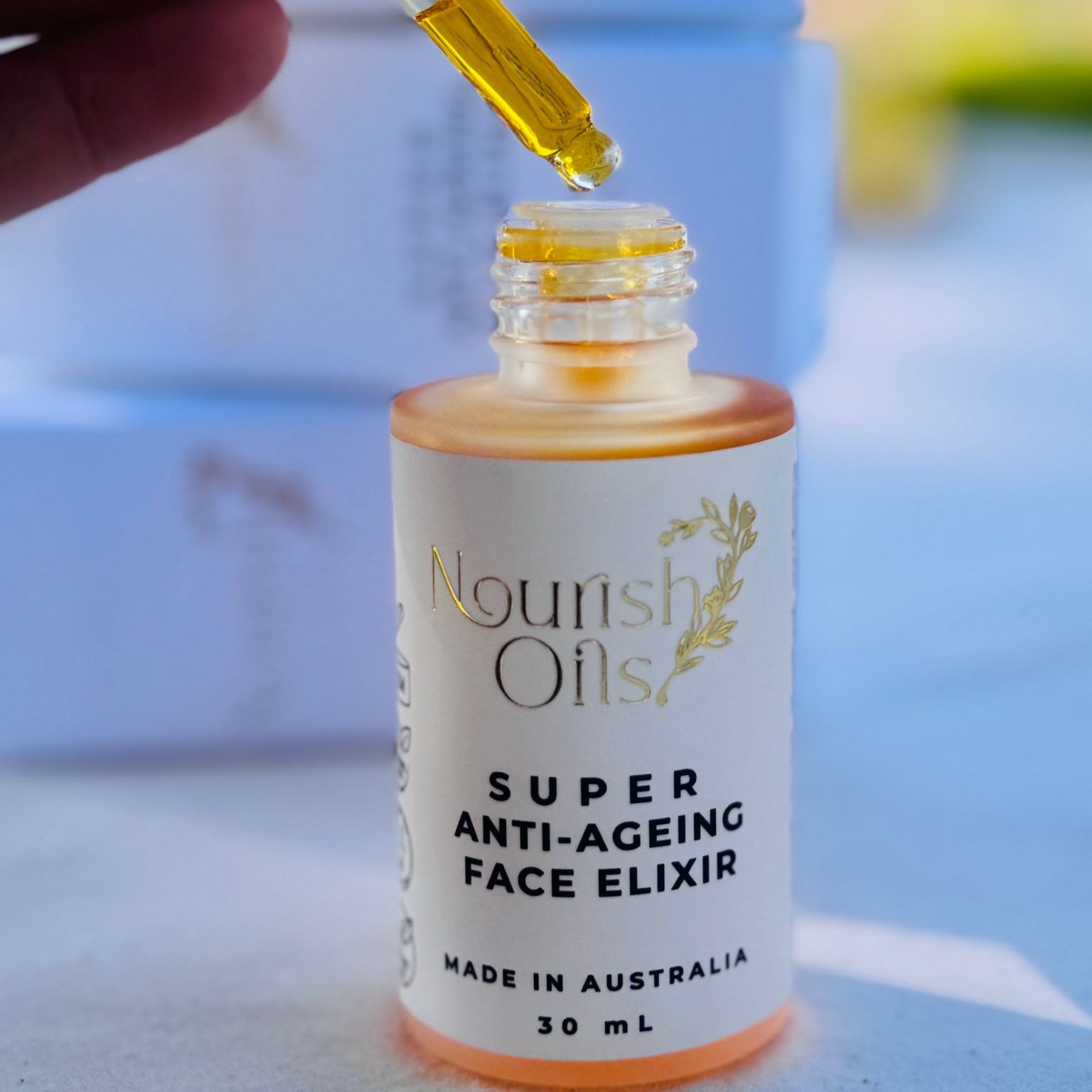 Bottle of Nourish Oils Super Anti-Ageing Face Elixir with a dropper being used.