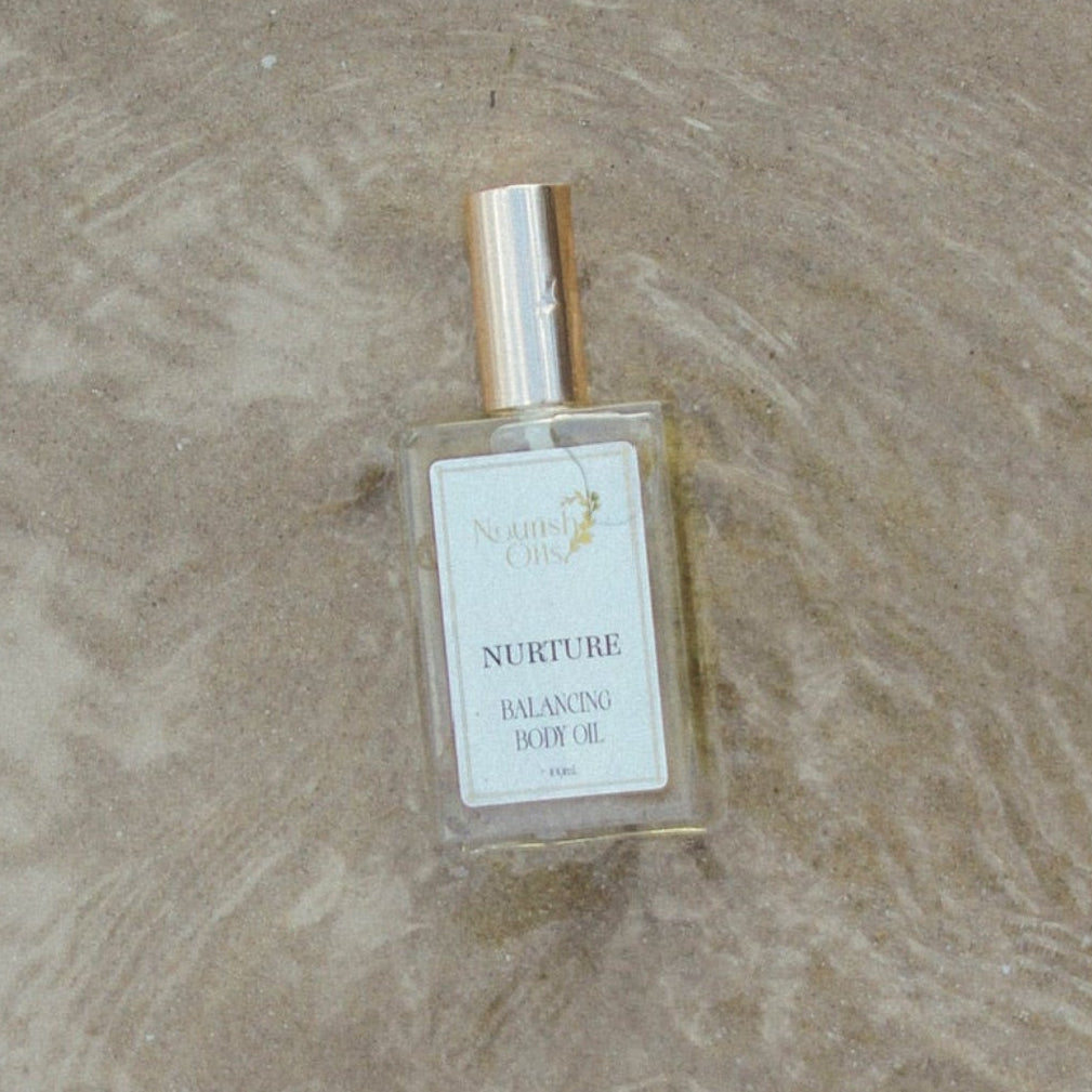A small rectangular perfume bottle labeled 'SUSPENSE' with a gold cap, placed on a textured beige stone surface.