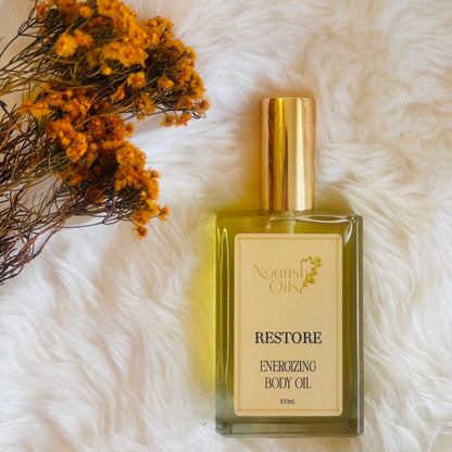 Restore Body and Massage Oil by Nourish Oils in a rectangular glass bottle with a gold cap, featuring an energizing blend of grapefruit and bergamot for immune support and vitality.
