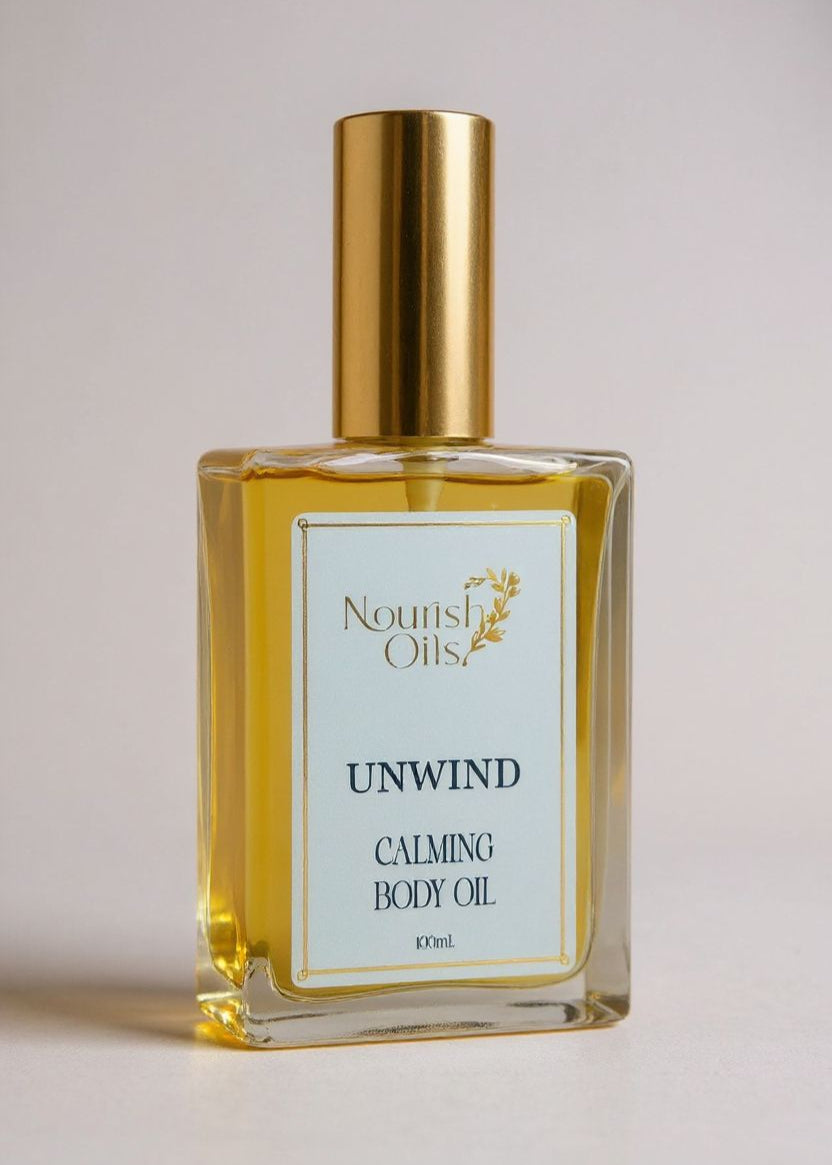 Bottle of Nourish Oils Unwind Calming Body Oil with gold cap on a light background