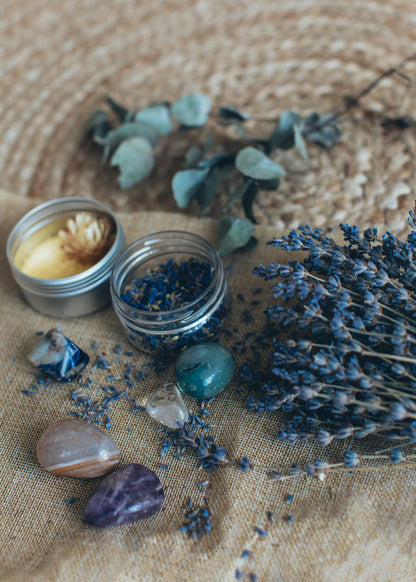 Candle, small jar, and dried lavender on a textured surface